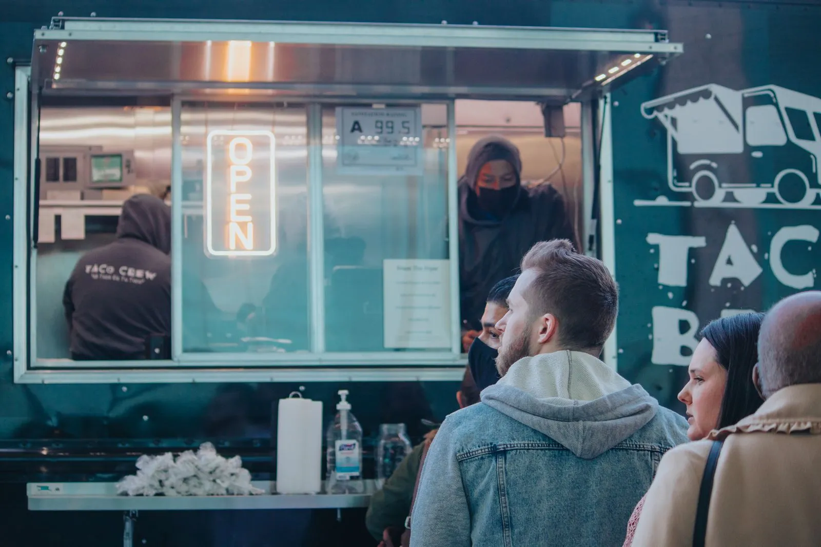 Diverse group of adults waiting in line at a taco food truck in High Point, NC.